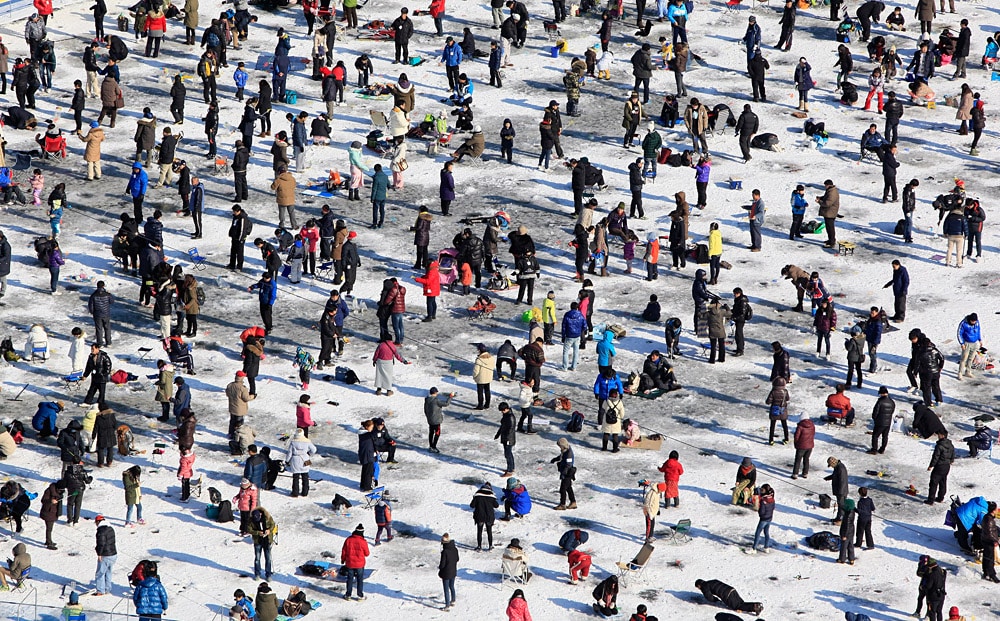 HWACHEON-GUN, SOUTH KOREA - JANUARY 07:  Anglers cast lines through holes into a frozen river during an ice fishing competition at the Hwacheon Sancheoneo Ice Festival on January 7, 2012 in Hwacheon-gun, South Korea. The annual Hwacheon Sancheoneo (Mountain Trout) Ice Festival attracts millions of visitors annually who gather to try thier luck at ice fishing with traditional lures or with bare hands. The three-week long event features several winter sports and games as well as an ice scultpure competition and takes place in what is considered the first region of Korea that freezes over during winter.  (Photo by Chung Sung-Jun/Getty Images)